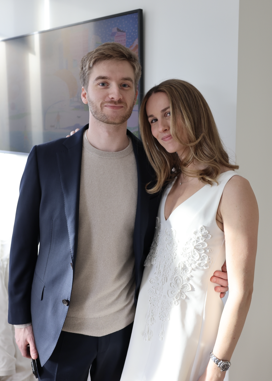 Annie and Nick together — Nick in a navy blazer with his arm around Annie in a white dress