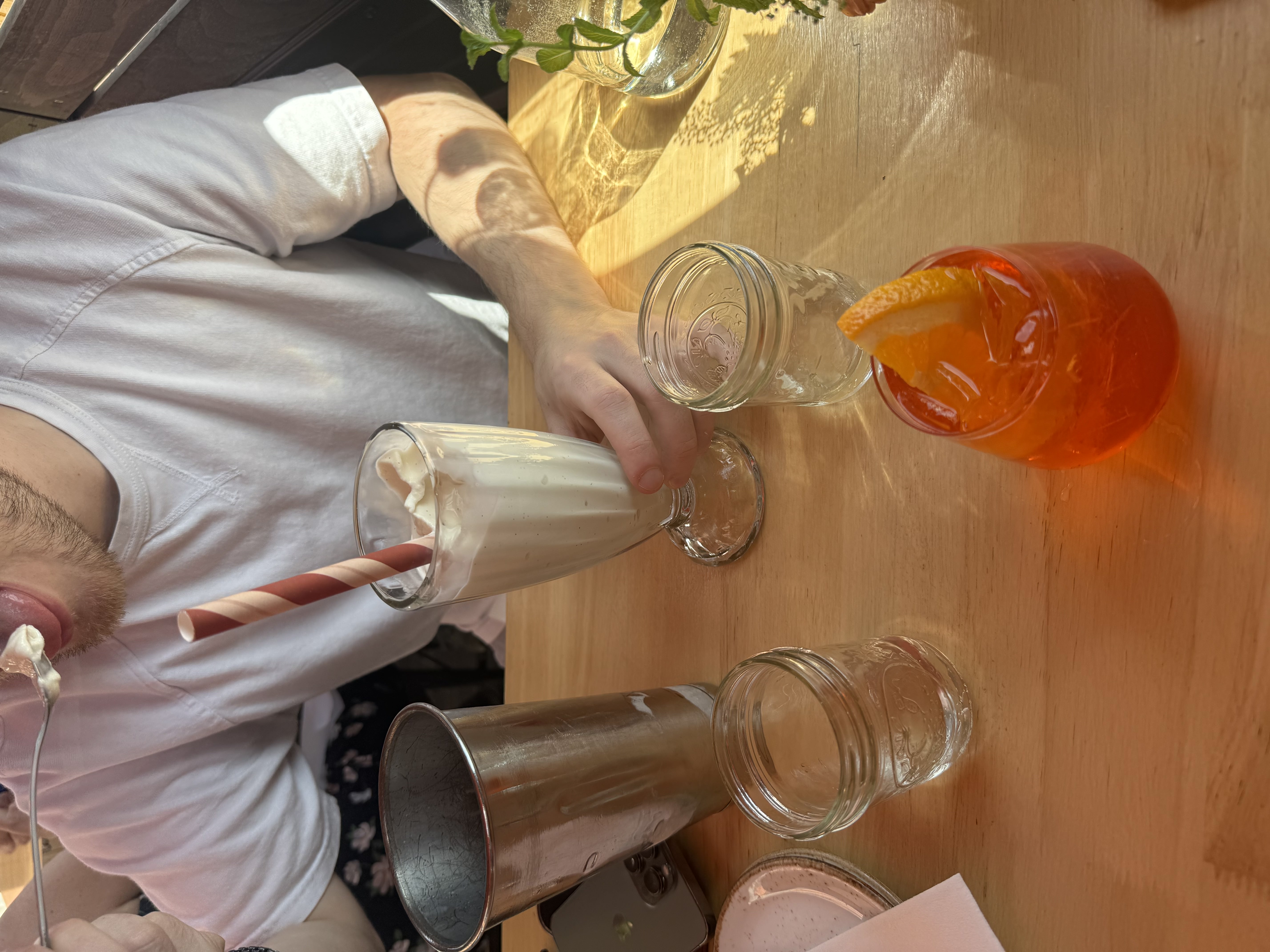 A milkshake and an Aperol spritz at a sunlit lunch table